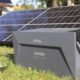 Das Bild zeigt die Solarbank nahe Solarmodulen auf Gras.