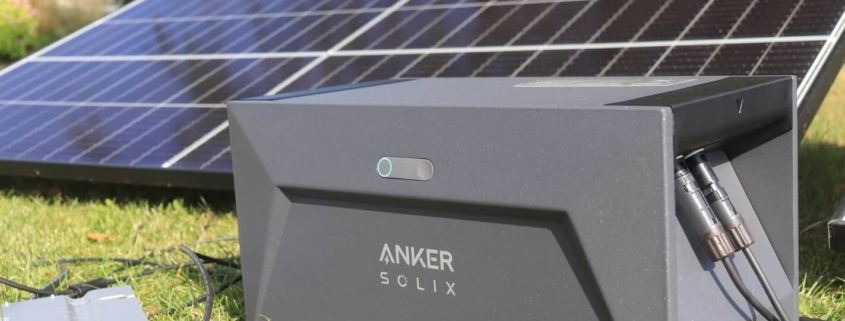 Das Bild zeigt die Solarbank nahe Solarmodulen auf Gras.