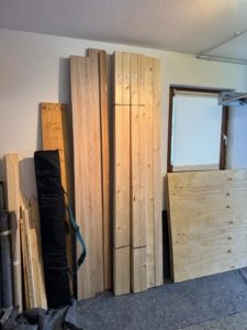 Holzplatten und Balken übersichtlich an der Garagenwand gelagert für den Werkbankbau